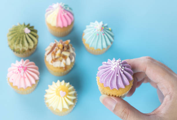 istock Hand holding purple cupcake with colorful cupcake on the background 904316568