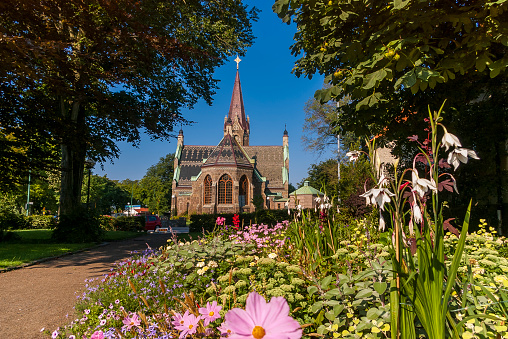 a stone church in summer light and flowerbed in foreground