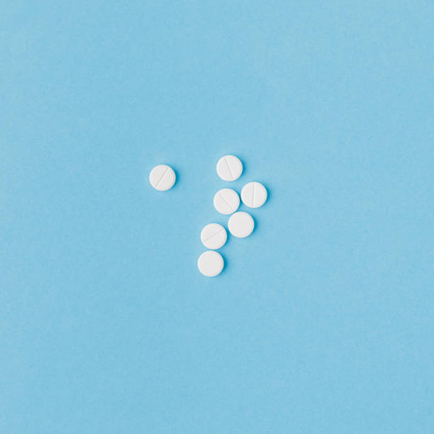 istock scattered white pills isolated on blue background 904331674