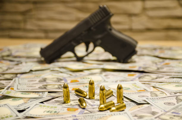 istock The blurred weapon with bullets laid down on blurred dollars. 904335890