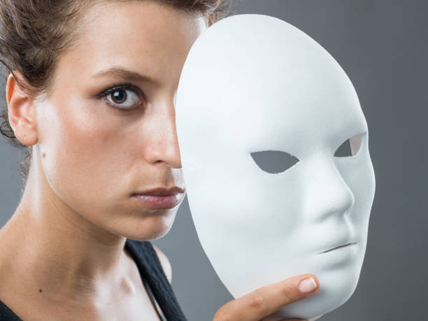 donna con i capelli castani e gli occhi che sbirciano dietro la maschera bianca - carnival mask women party foto e immagini stock