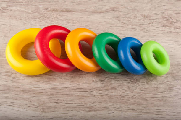 istock Row of multicolored plastic rings lay on wooden background 904358340