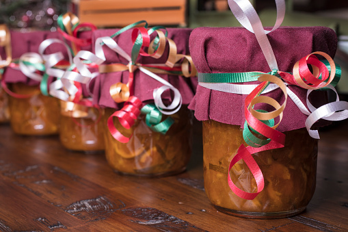 Mason jars filled with homemade orange marmalade decorated for the holidays as Christmas gifts