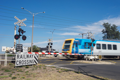 A commuter train passes through a railway level crossing on Eel Race Road, Seaford, Melbourne.