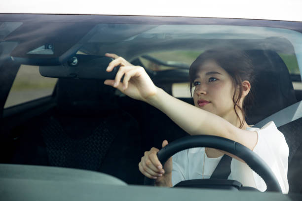 young woman driver checking a rear view mirror. - woman in mirror backview imagens e fotografias de stock