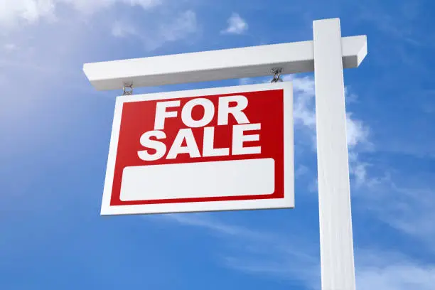 A real estate agents for sale sign with perfect blue sky background.