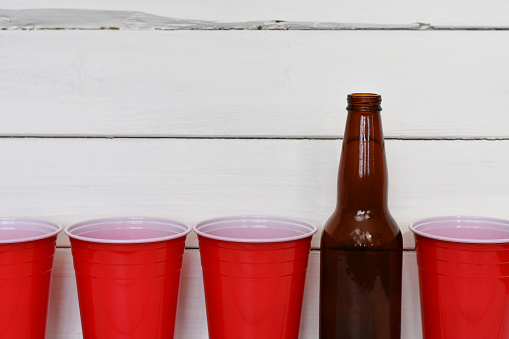 A close up image of red solo drinking cups and brown beer bottles.