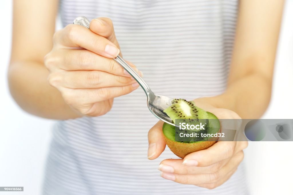 A woman hold kiwi fruit and slice with spoon for eating on isolated white background. concept of nutrition, healthy, beauty and diet. Kiwi Fruit Stock Photo