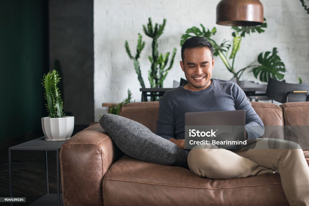 Young Asian man working at home. Young Asian man using the laptop in the living room. Men Stock Photo