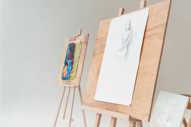 istock easels with artistic paintings in empty art studio on grey 904442112