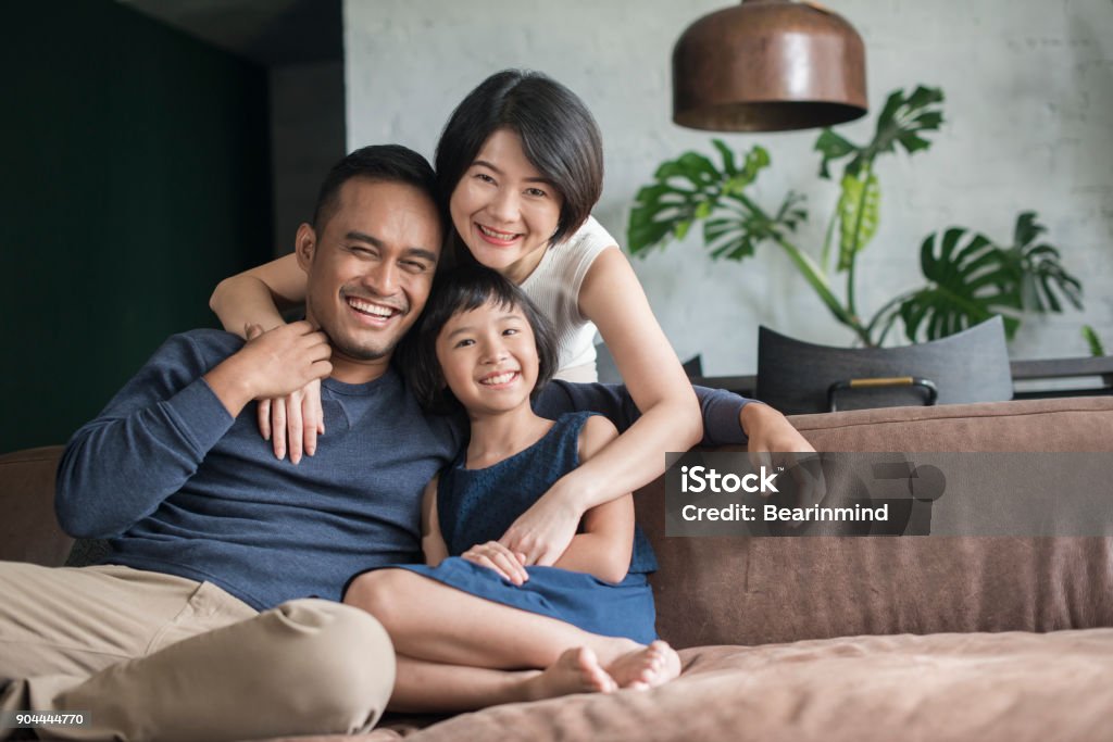 Young Asian family at home. Young Asian parents with only child relaxing on the sofa in the living room. Family Stock Photo
