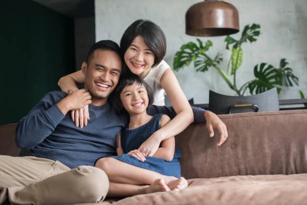 Young Asian family at home. Young Asian parents with only child relaxing on the sofa in the living room. asian ethnicity family stock pictures, royalty-free photos & images