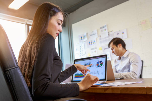istock Business woman working with Laptop computer and documents on the table and colleagues in background 904453138