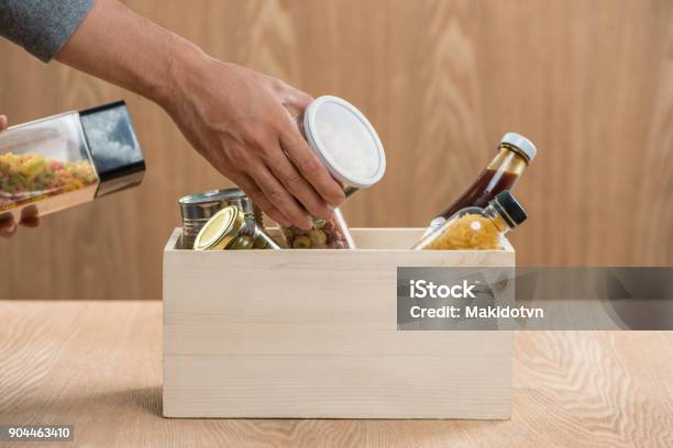 Volunteer With Donation Box With Food Stuffs On Wooden Background Stock Photo - Download Image Now