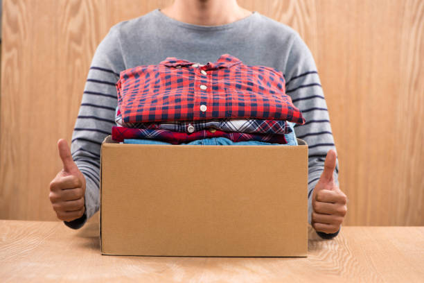 istock Donation box for poor with clothing in male hands 904465562