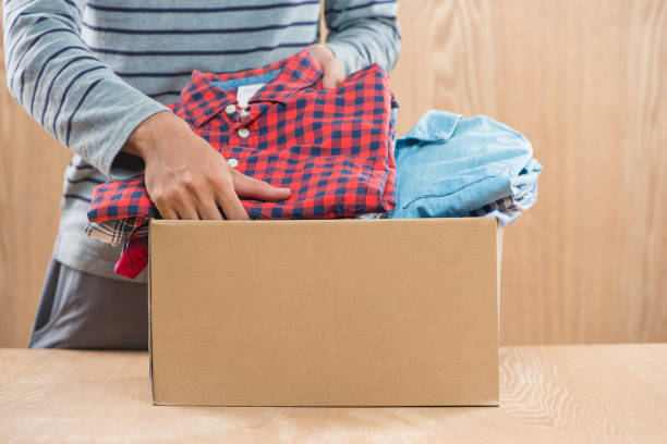 istock Donation box for poor with clothing in male hands 904465660