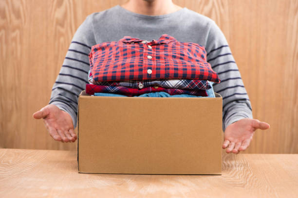 istock Donation box for poor with clothing in male hands 904465686