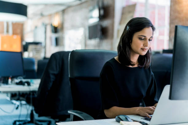 istock Young businesswoman using laptop at desk in office 904465862