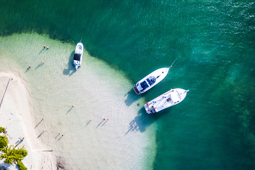 Aerial view of sup boards in blue sea at sunset in summer. Man and woman on floating canoe in Transparent azure water. Lefkada island, Greece. Tropical landscape. Kayaks. Active travel. Top view