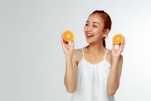 jovem linda mulher asiática com fatias de laranja nas mãos, isoladas no fundo branco, conceito de estilo de vida saudável - isolated on white fun orange food - fotografias e filmes do acervo