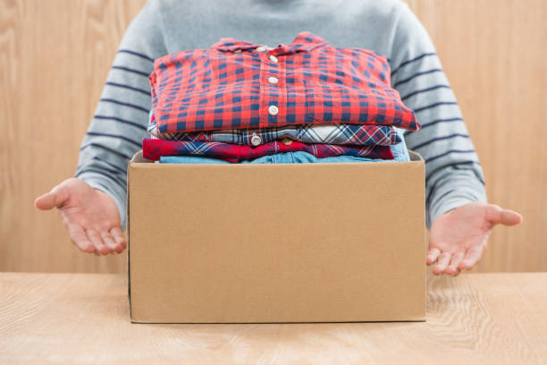 istock Donation box for poor with clothing in male hands 904472986