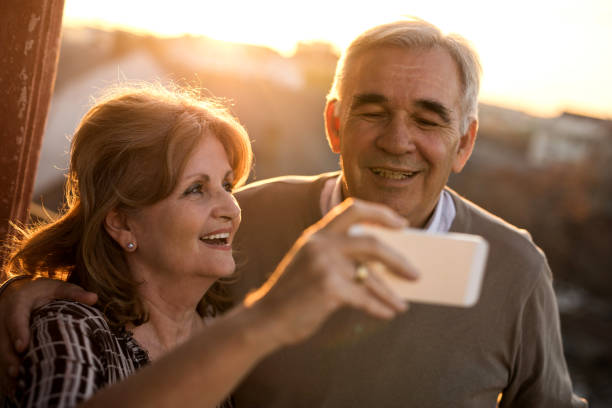 istock Embraced senior couple taking a selfie with mobile phone at sunset. 904476998