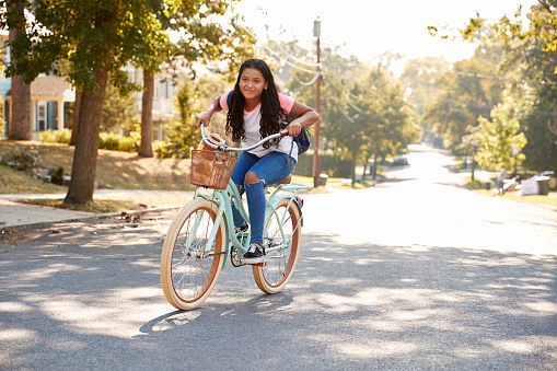 Girl Riding Bike Along Street To School