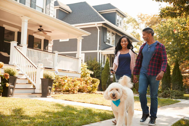 couple walking dog along suburban street - suburb imagens e fotografias de stock