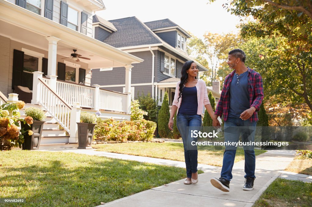 Couple Walking Along Suburban Street Holding Hands Walking Stock Photo