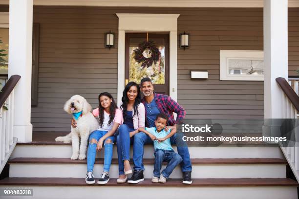 Family With Children And Pet Dog Sit On Steps Of Home Stock Photo - Download Image Now