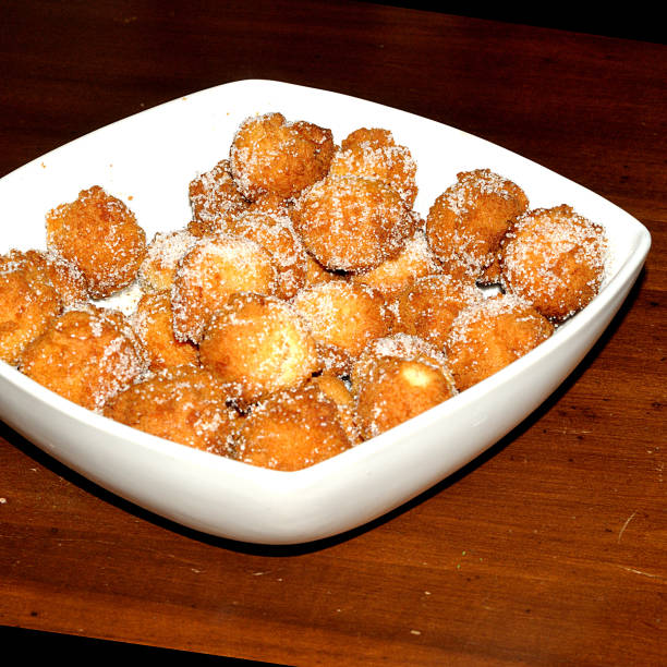 Castagnole, sugared pancake, in a square tray over rustic table of dark wood