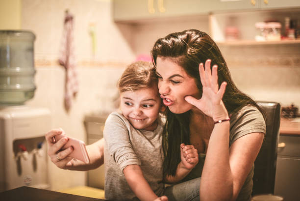 istock Mother and daughter take a self portrait with funny face, using smart phone. 904483382