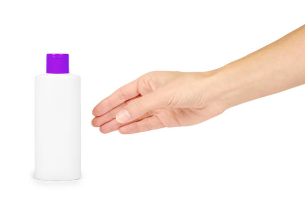 istock Plastic white shampoo bottle with orange cap in hand isolated on white background. Gel dispenser for hair care. Container with body lotion. 904483582
