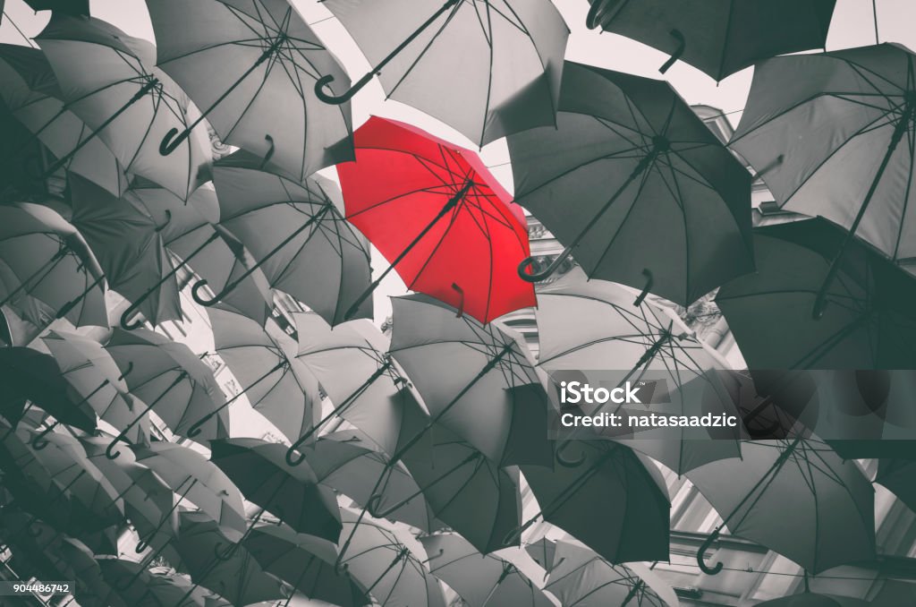 Stand out from the crowd Red different umbrella in mass of black umbrellas Black And White Stock Photo