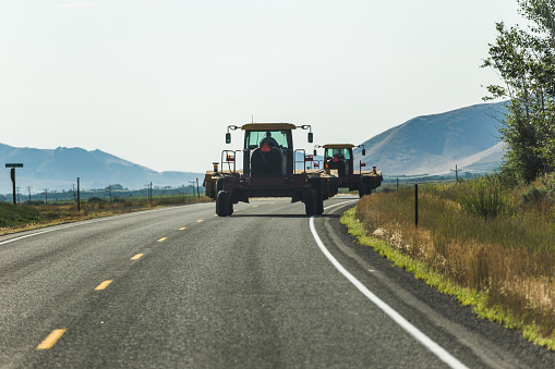 Heavy farm equipment driving down a rural highway.
