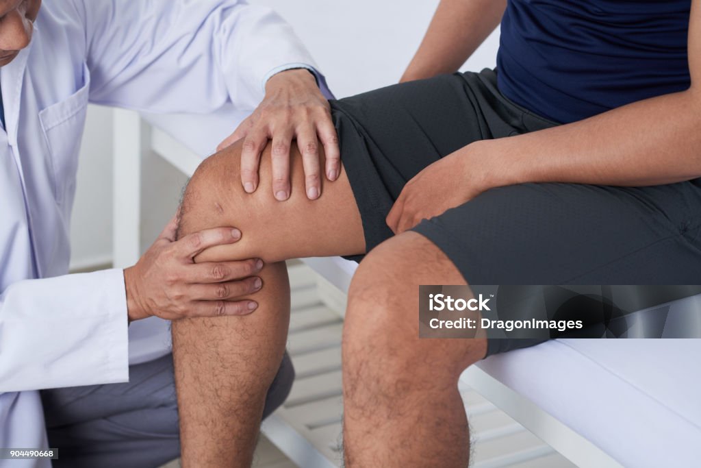 Examining knee Doctor cheking knee of male patient Knee Stock Photo