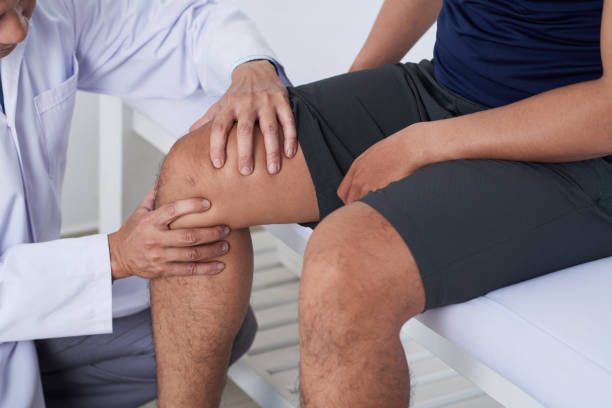 Examining knee Doctor cheking knee of male patient checking sports stock pictures, royalty-free photos & images