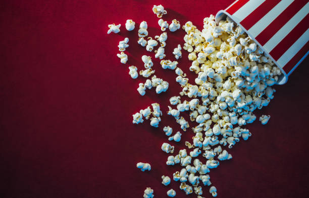 Popcorn and cinema Spilled popcorn on a red background, cinema, movies and entertainment concept popcorn stock pictures, royalty-free photos & images