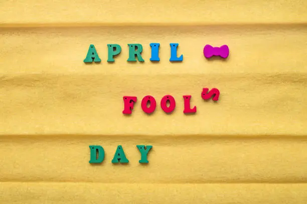 Photo of Day of the Fool Day, inscription from multi-colored letters on a yellow paper background