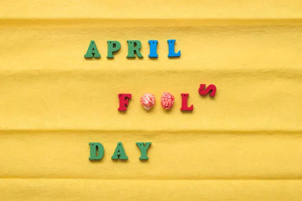 Photo of Day of the Fool Day, inscription from multi-colored letters on a yellow paper background