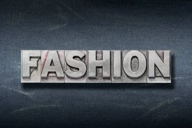 fashion word made from metallic letterpress on dark jeans background