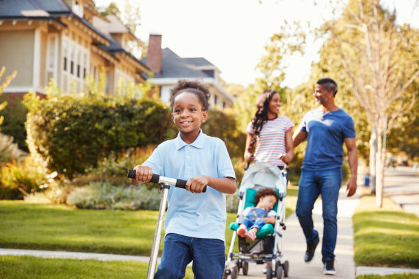 istock Couple Push Daughter In Stroller As Son Rides Scooter 904506002
