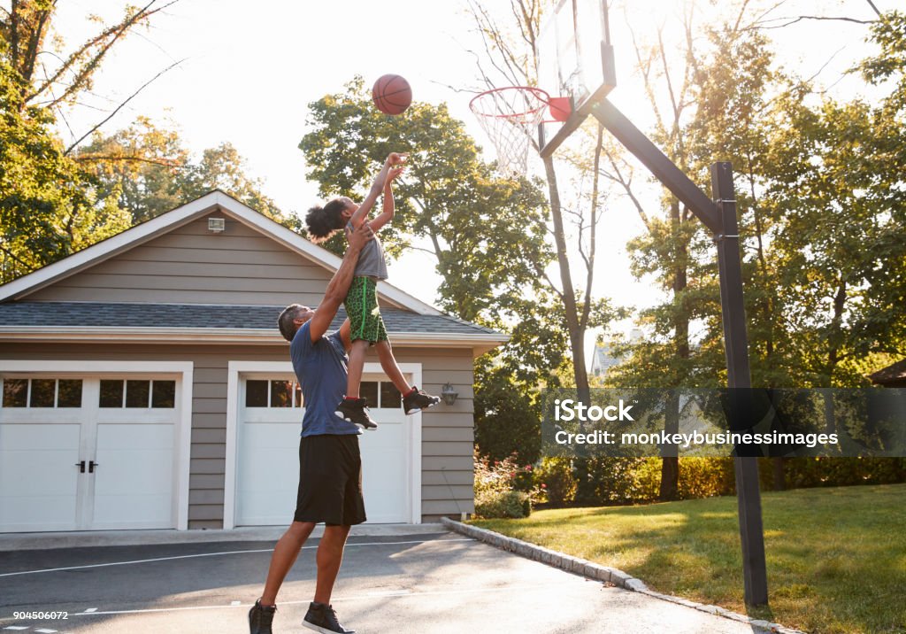 Father And Son Playing Basketball On Driveway At Home Basketball - Sport Stock Photo