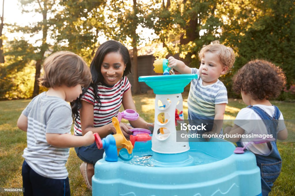 Mother And Young Children Playing With Water Table In Garden Toddler Stock Photo