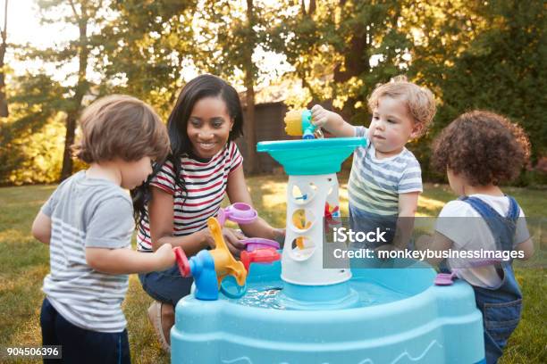 Mother And Young Children Playing With Water Table In Garden Stock Photo - Download Image Now