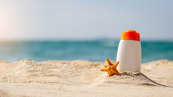 Bottle of sunscreen lotion and starfish on tropical beach, Beach accessories and summer concept, copy space