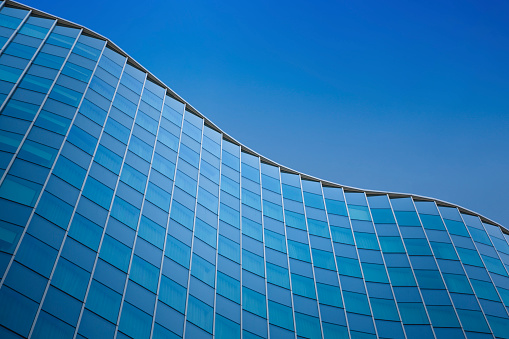 Close up of a modern architecture with blue sky background - glass building exterior