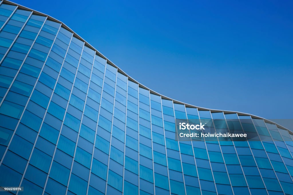 Close up of a modern architecture background - glass building exterior Close up of a modern architecture with blue sky background - glass building exterior Architecture Stock Photo