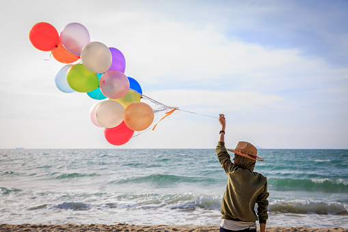 Young woman holding colorful balloon on the beach