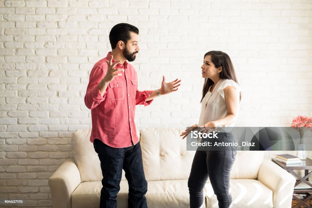 Couple having argument at home Young hispanic couple having argument at home in the living room Couple - Relationship Stock Photo